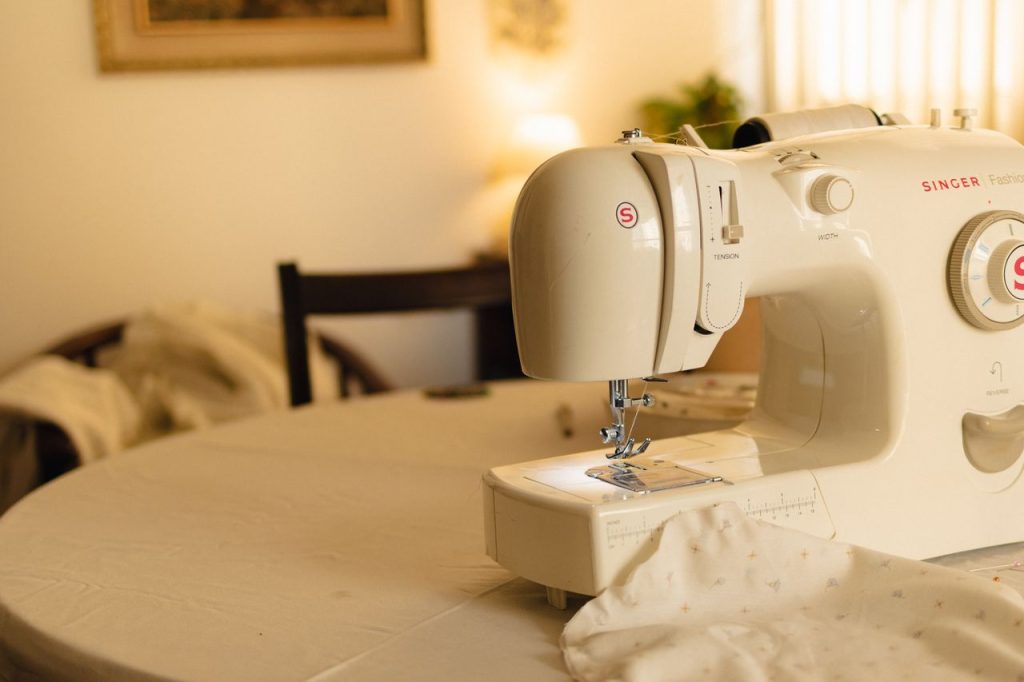 White sewing machine on a table in a cozy indoor setting, with soft lighting.