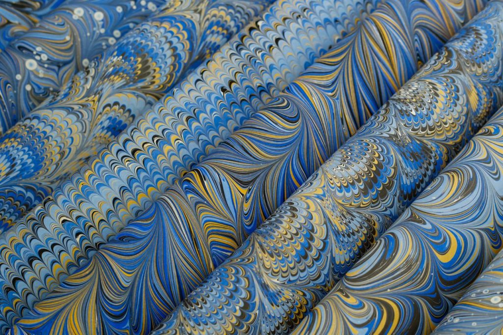Detailed view of vibrant blue marbled paper with intricate swirling patterns, perfect for art and design projects.