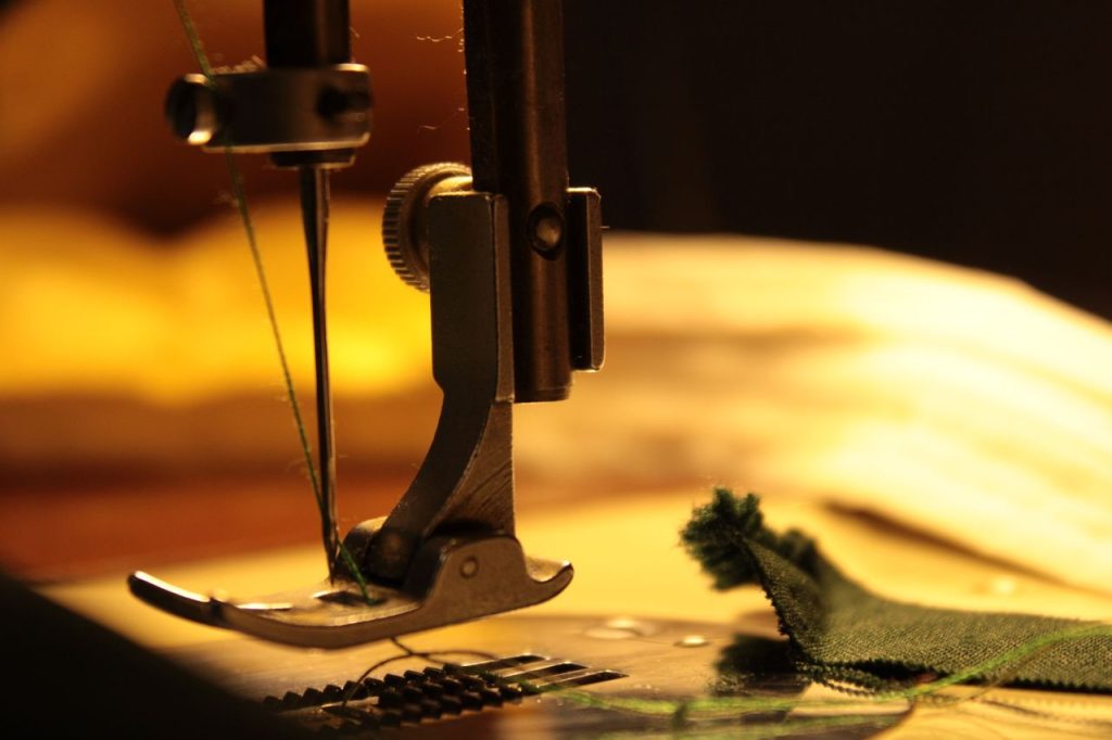 Detailed view of a sewing machine needle stitching fabric, highlighting craftsmanship.