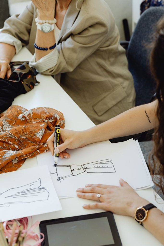 Two fashion designers working on dress sketches with fabric samples.